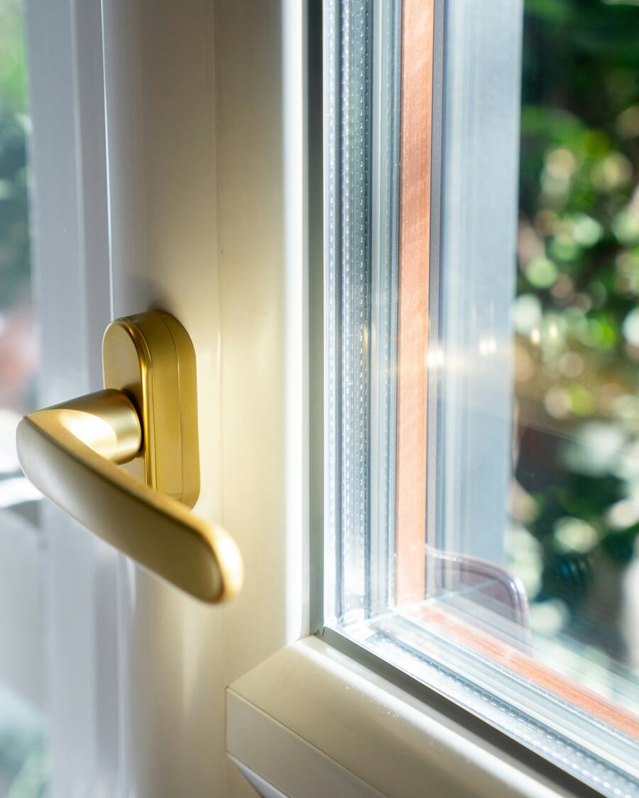 Caixilharia em PVC branco com puxador, janela aberta para o exterior.