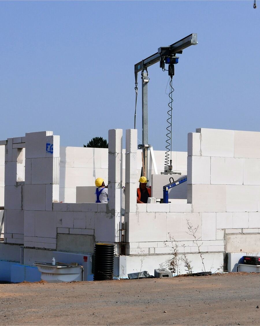 Moradias em construção com paredes em alvenaria e grua, num bairro novo.