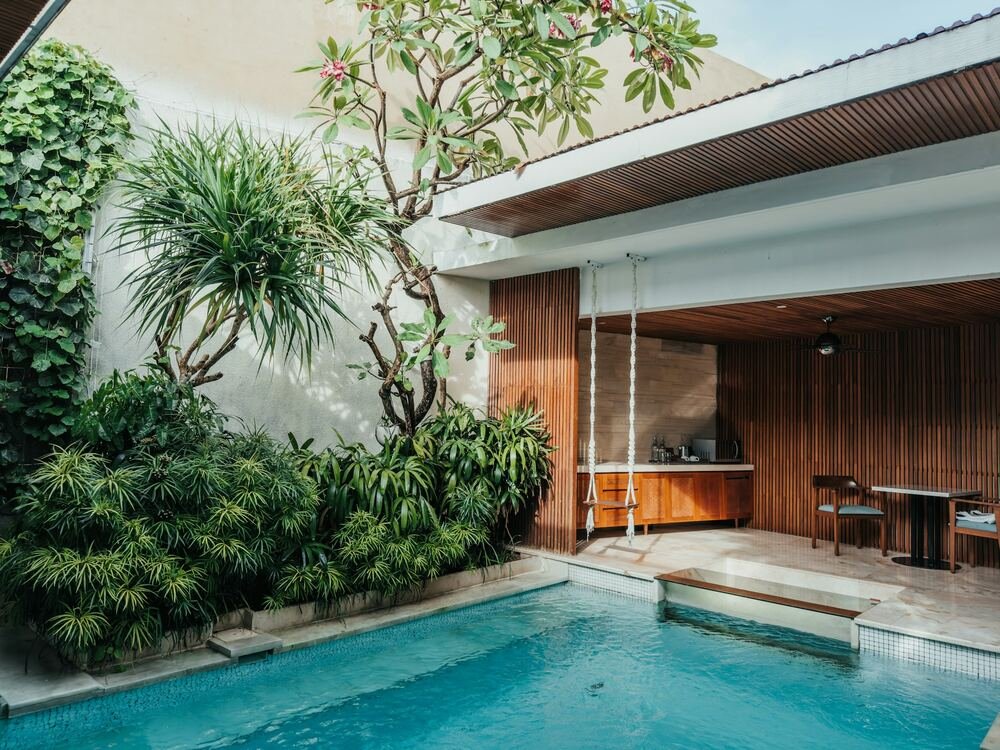Piscina junto a uma casa com jardim e mesa exterior.