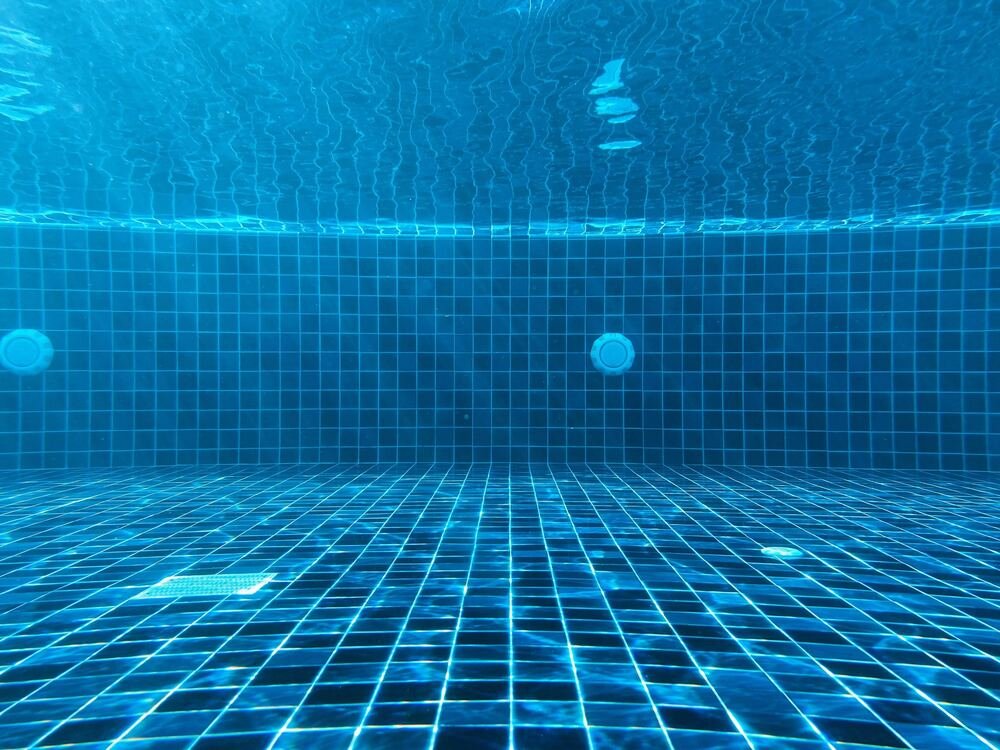 Vista subaquática de uma piscina revestida a pastilha azul.