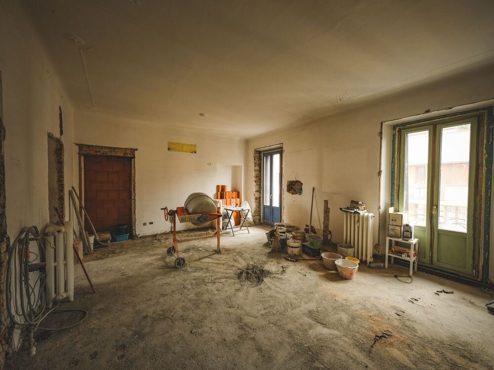 Sala ampla em obra, com materiais e ferramentas.
