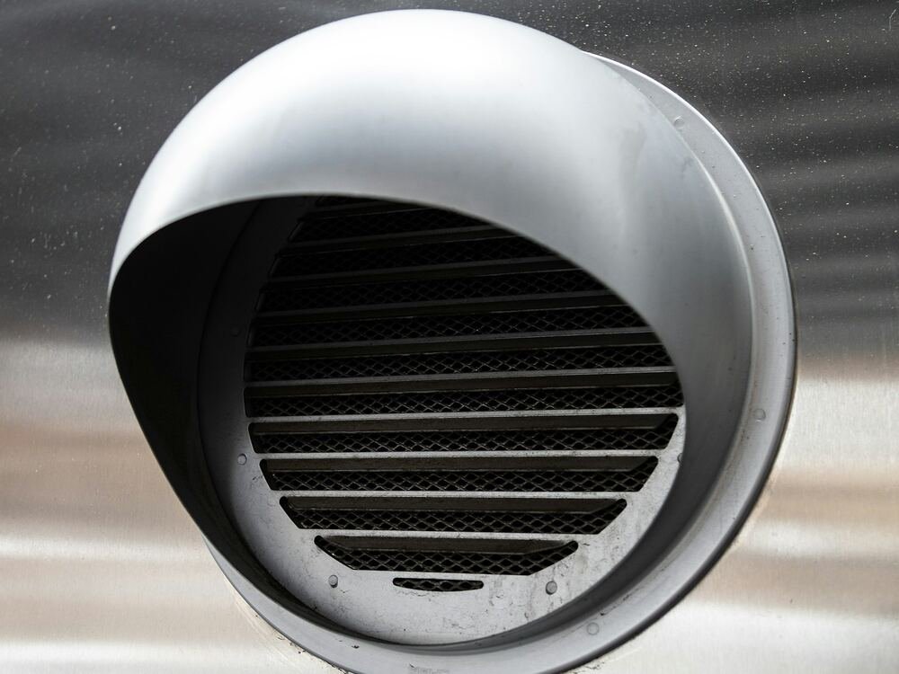Grelha exterior de ventilação em aço inoxidável numa fachada.
