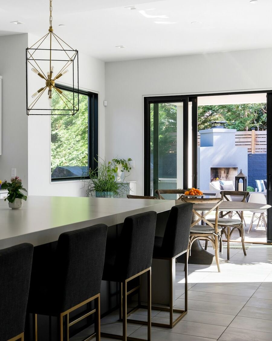 Cozinha remodelada com ilha e grandes portas envidraçadas abertas para o pátio.