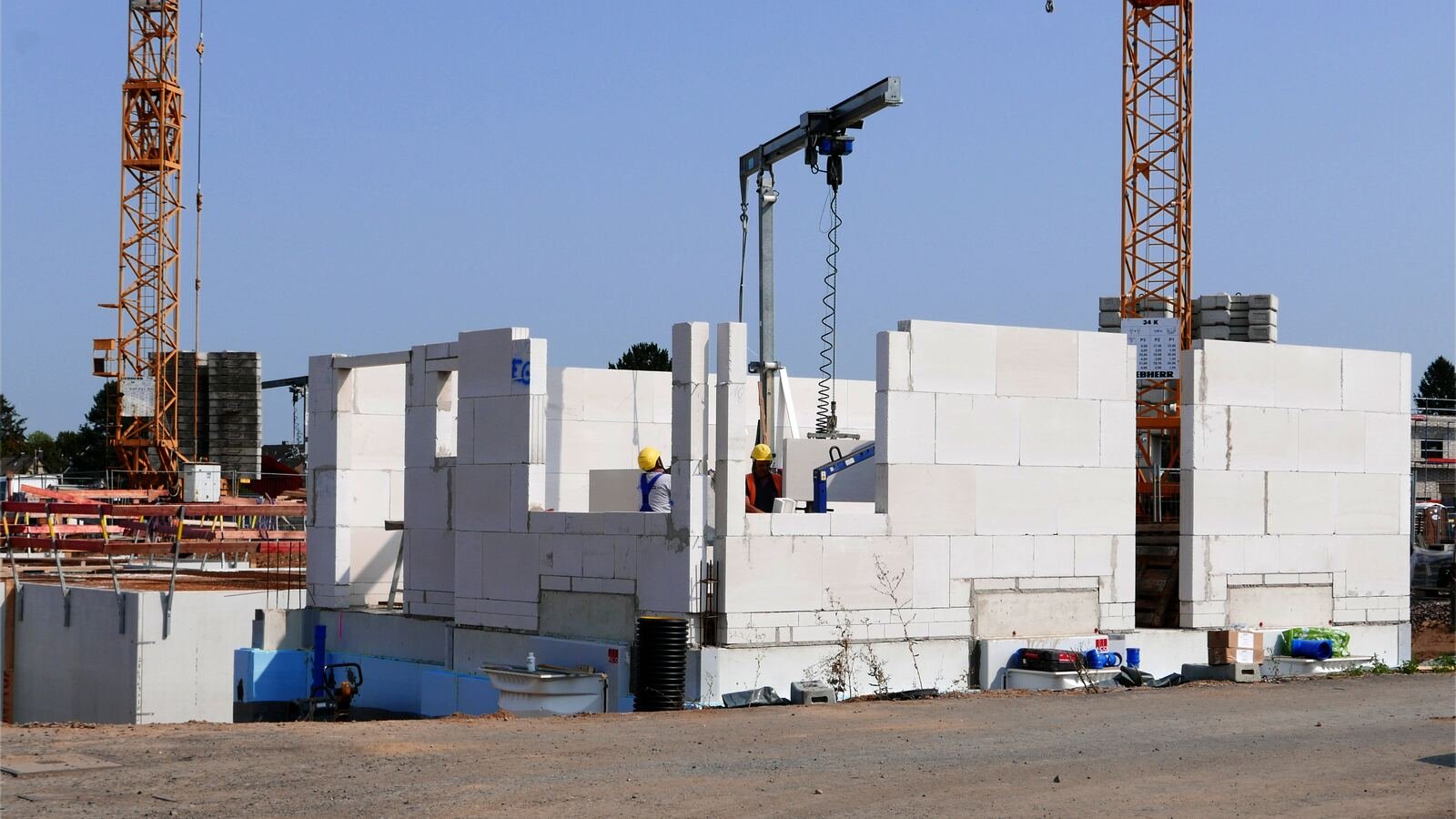 Moradias em construção com paredes em alvenaria e grua, num bairro novo.